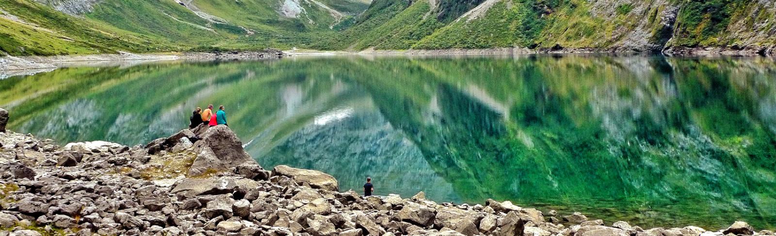 picture of a group of hikers resting on the shores of a lake.