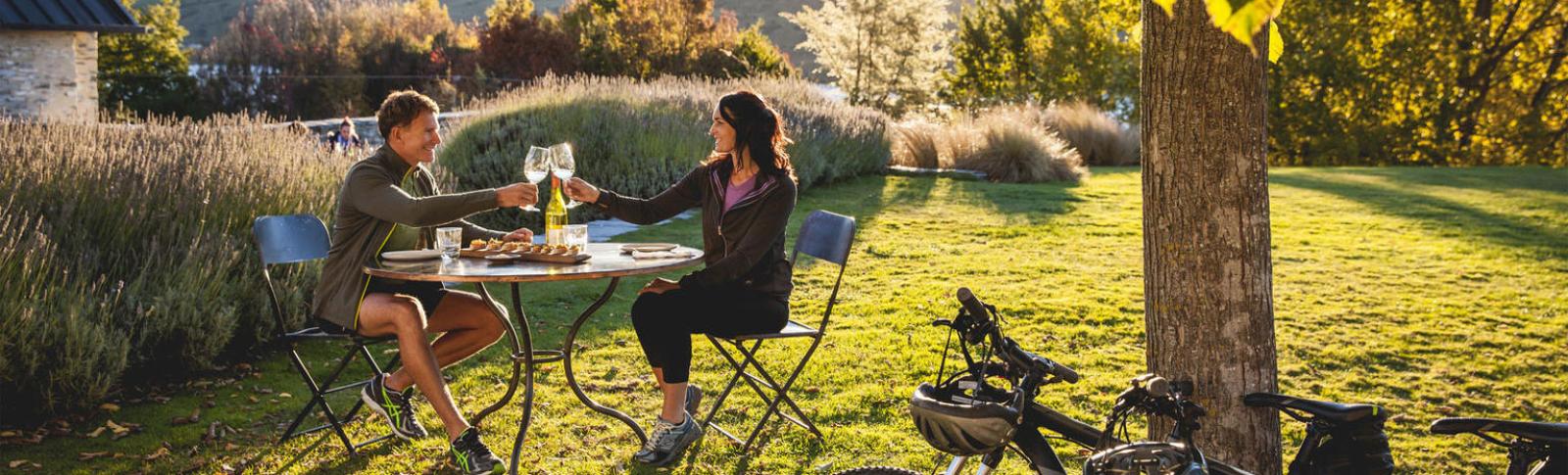 Couple cycling in Marlborough stopping for a glass of wine in a vinyard